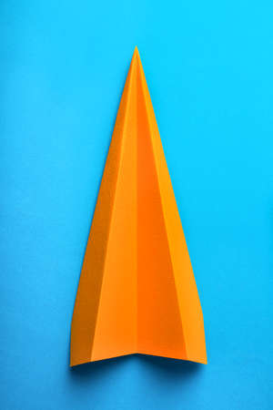 Photo of orange origami paper airplane on blue paper backgroundの写真素材