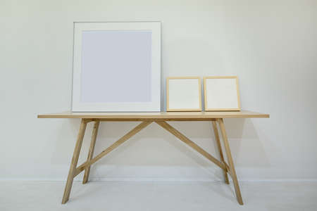 Three empty decorative frame for paintings or photographs on the oak table. Minimalism. Style loft.
