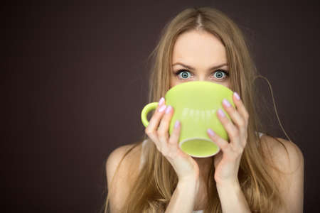Woman drinking from a large  and green cupの写真素材