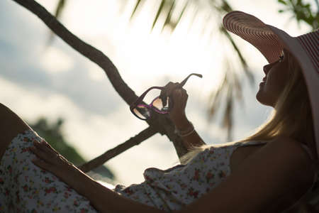 silhouette of girl in hat lying on the beach restingの写真素材