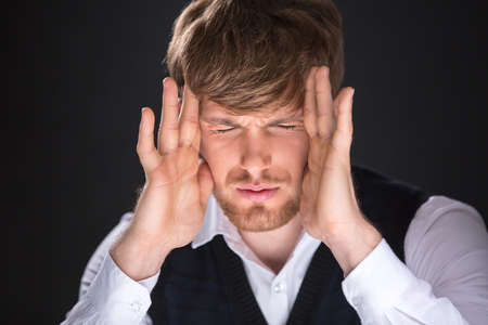 Tired handsome man with hands over his face. Feeling headache.の写真素材