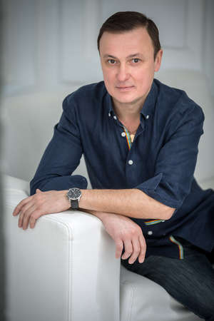 Man sitting in the sofa with a slight smile and looking at the camera. Studio in the Kiev, Ukraine.