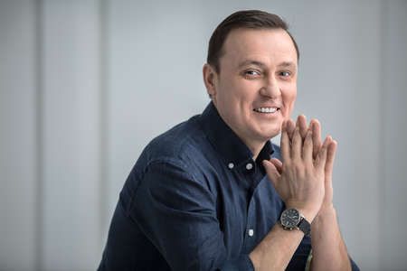 Man sitting with a slight smile and looking at the camera with his arms crossed. Studio in the Kiev,...