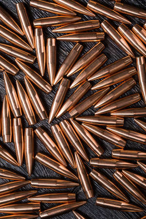 Placer copper bullets on a dark wooden background, shot in the studio.の写真素材