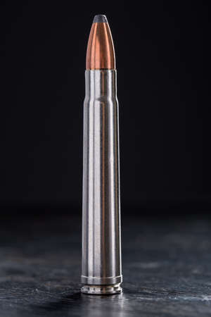 One cartridge with copper bullet and lead tip, sleeve silver on the black background.の写真素材