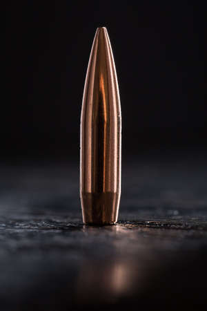 One copper bullet with bright reflections on a black backgroundの写真素材