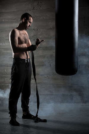 Boxer pulls bandages for boxing beside a large black pearsの写真素材