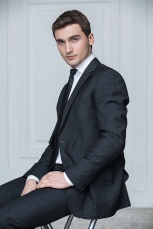 Solid young man in black suit and tie. Studio portrait photography business.の写真素材
