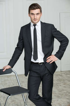 Solid young man in black suit and tie. Studio portrait photography business.の写真素材