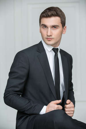 Solid young man in black suit and tie. Studio portrait photography business.の写真素材