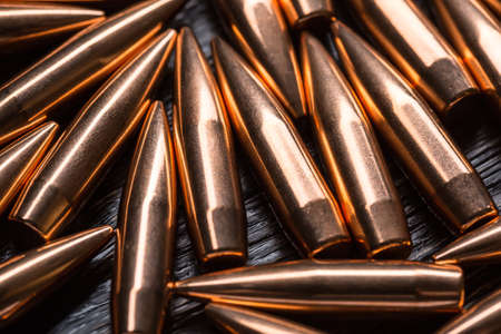 Placer copper bullets on a dark wooden background, shot in the studio.の写真素材