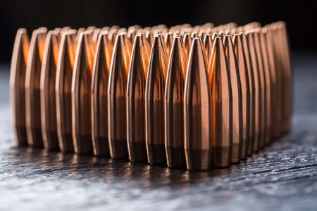 Macro shot of copper bullets that are in many rows to form a triangle on a black wooden background.の写真素材