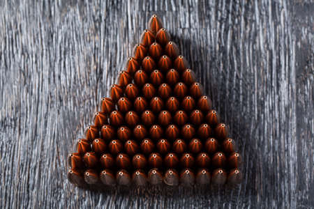 Macro shot of copper bullets that are in many rows to form a triangle on a black wooden background.の写真素材
