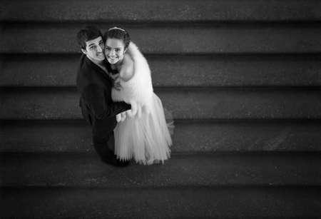 Couple in love is embracing on the stairs and looks up with a smile. Black and white photo.の写真素材