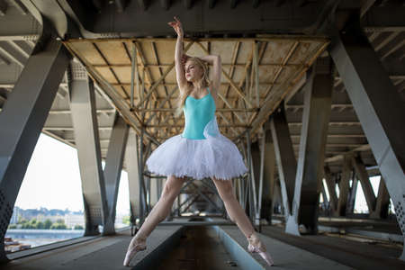 Graceful ballerina in white tutu in the industrial background of the bridge.の写真素材