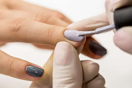 Photos of manicure at the salon. Master gets a new paint gray fingers on different - different...