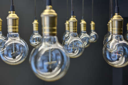 Edison lamps suspended from the ceiling in a regular geometric sequence. One lamp in focus. The rest of the optical out of focus.の写真素材