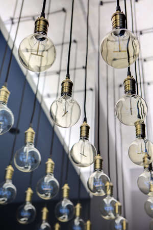 Edison lamps suspended from the ceiling in a regular geometric sequence. One lamp in focus. The rest...