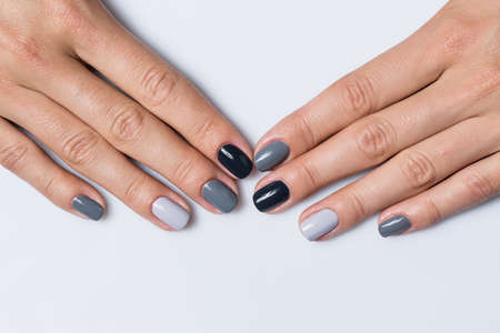 Feminine hand with a stylish gray manicure isolated on white background close up. Each nail is made up of different shades of gray varnish.の写真素材