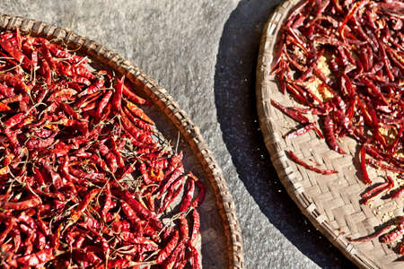 Dried chili peppers in a wicker basketの写真素材