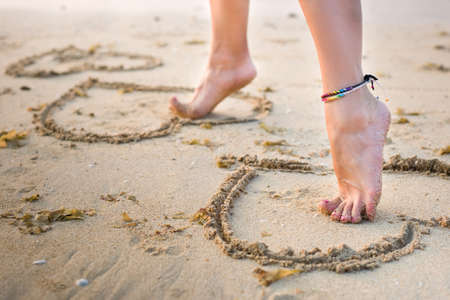 womans legs on beach sand take a step forwardの写真素材