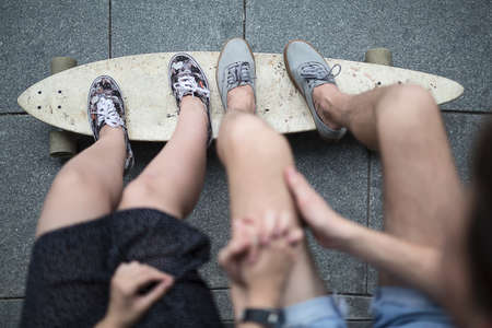 Feet couple of teenagers in sneakers standing on longboard closeup. The top point of shooting.の写真素材