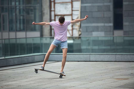 Stylish teenager makes a jump on a longboard tricks on urban city background.の写真素材