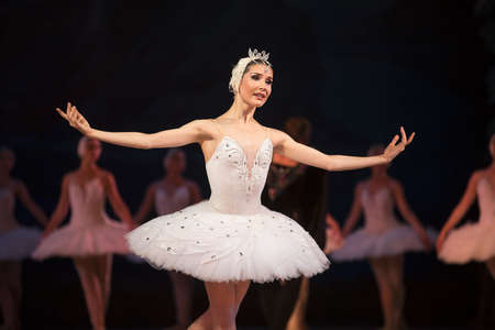 Prima ballerina white swan on stage dancing gracefully against other dancers. Ballet Swan Lake, the...