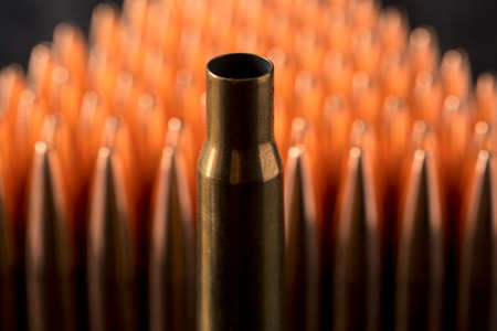 Macro shot of copper bullets that are in many rows to form a triangle on a black wooden background.の写真素材