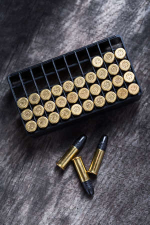 Scattering of small caliber cartridges on a wooden background. Other cartridges cartridges lies in...