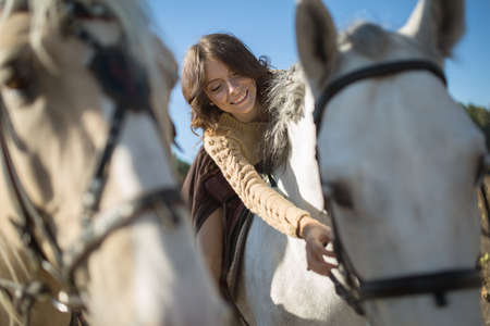 Beautiful girl riding a horse leaned over and stroked her face with a slight smile.の写真素材