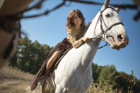 Beautiful girl riding a horse leaned over and stroked her face with a slight smile.の写真素材
