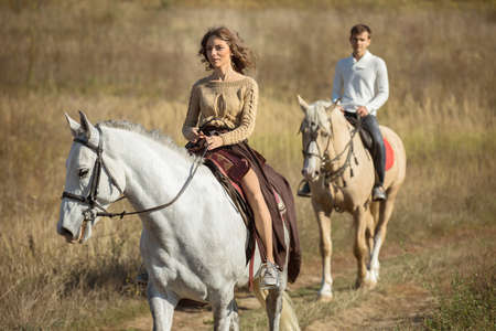 Young couple in love riding a horse walking on the background of autumn nature in a beautiful field.