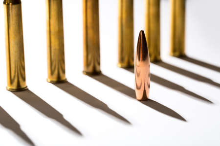 Macro shot of bullet casings on a white studio background. Sleeve casts a shadow on the tough end of which is shiny copper bullet.の写真素材