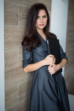 Business portrait slim pretty girl in a strict office clothes with closed laptop in hand.