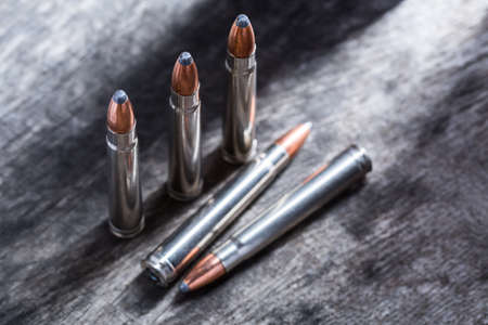 Cartridges silver with copper large-caliber bullets in a gray textural composition on wooden...