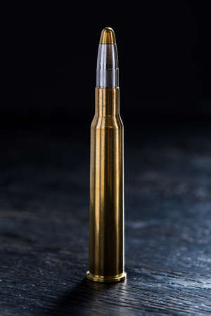 Large-caliber cartridge on a dark background with reinforced shiny brass bullet tip. Photographed in the studio.の写真素材