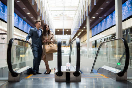 Man in a dark business suit and a beautiful woman in a bright coat on ekskalatore the mallの写真素材