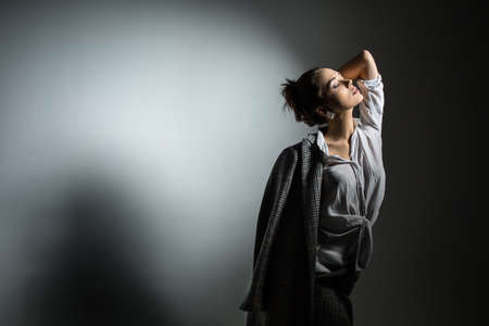 Portrait of a beautiful girl in stylish black coat shot in a cage in the studio on a white background. The girl in a sensual pose hung his coat over one shoulder.の写真素材