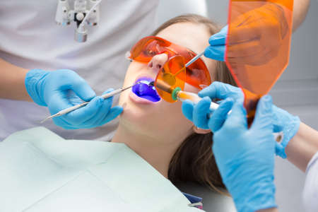 Girl patient in the dental clinic. Teeth whitening UV lamp with photopolymer composition.の写真素材