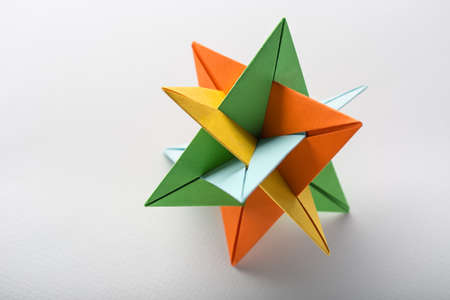 One star kusudama origami on the light background. It colored in orange, yellow, blue and green. Close-up photo. Horizontal.の写真素材