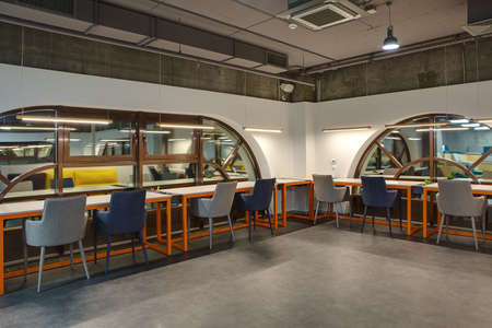 Room in a loft style. Two white walls with brown rounded windows. Upper parts of walls are concrete....
