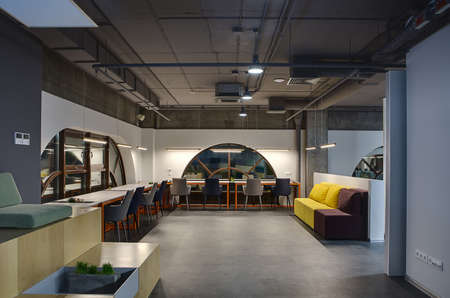 Hall in a loft style with white walls with brown rounded windows. Upper parts of walls are concrete....