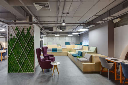 Interior in a loft style with a big zone with wooden benches and seats. Benches are decorated with...