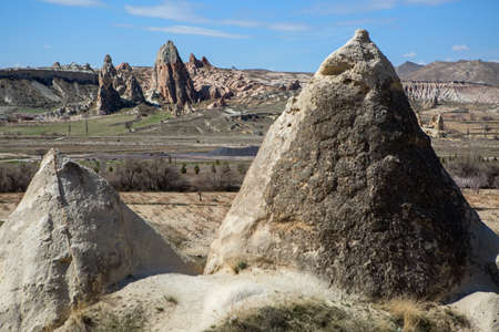 Two peaks of rocks on the background of valley with rock formation and blue sky with clouds.の写真素材