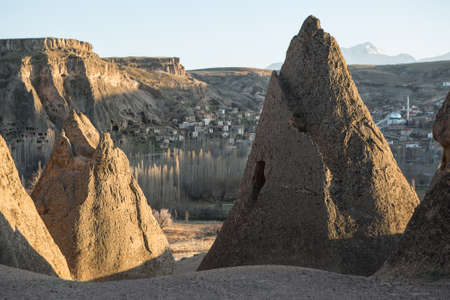 Rocks with houses carved into rock on the background of the old town in the valley and the sky. Sunlight touches the peaks of the rocks.の写真素材
