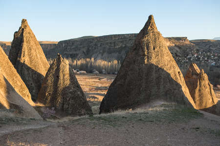 Several rocks on the background of the valley with mountains. On the left there is an old town. Sunlight touches the peaks of the rocks.の写真素材