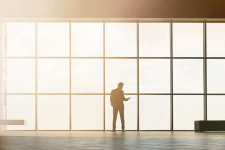 Stylish business man in the background of a large window in the floor. Model talking on the phone.の写真素材