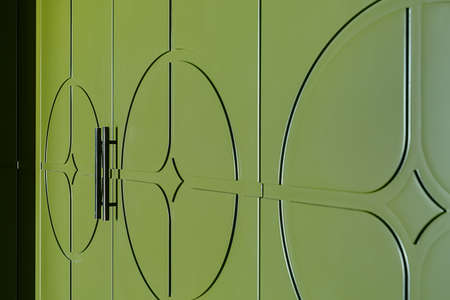 Part of the door of green texture wardrobe. Doorhandles are black. Close-up horizontal photo.の写真素材