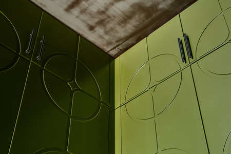Texture green wardrobes with black handles and a texture ceiling. Close-up horizontal photo. Indoors.の写真素材